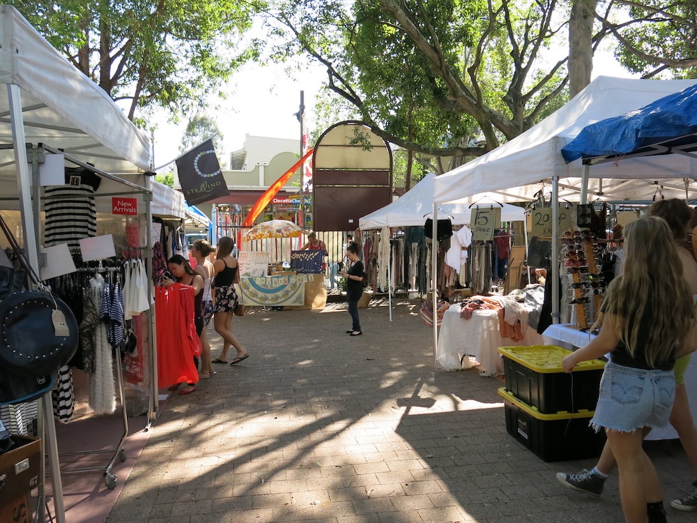 A handful of women walk among the tents of clothes and accessories in the Glebe Markets in Sydney