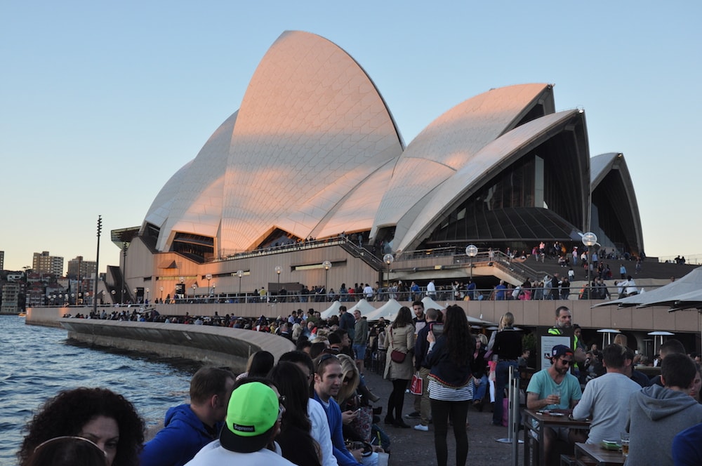Outside Sydney Opera House is crowded with people enjoying the view at dusk