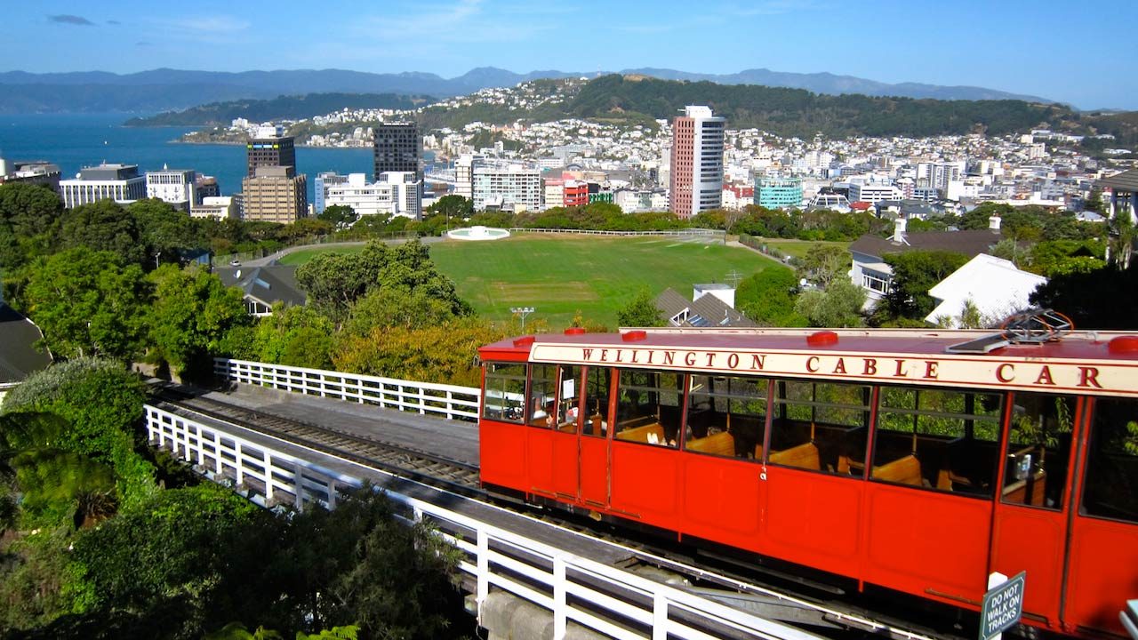 A red cable car traveling past a beautiful view of the city of Wellington