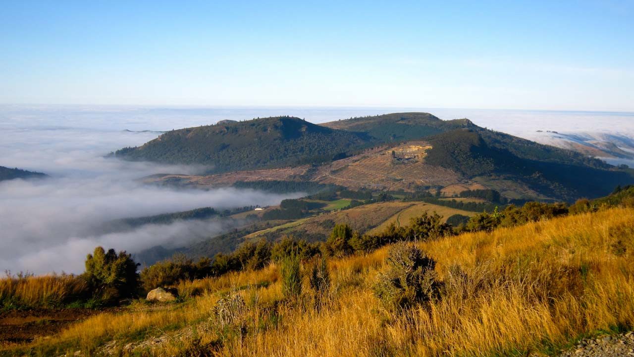 Grassy mountains peek out of the clouds in Dunedin, New Zealand