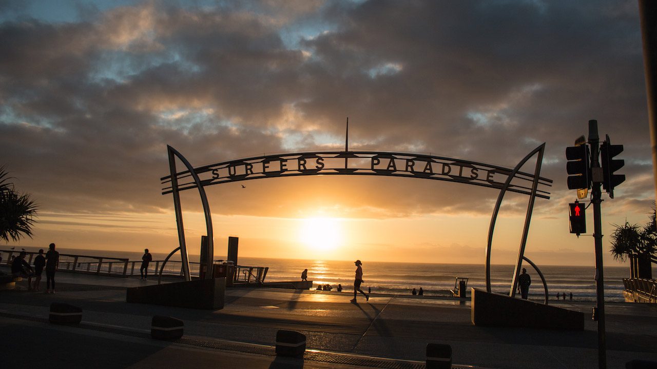 The sun setting on the beach behind the infamous Surfer's Paradise sign