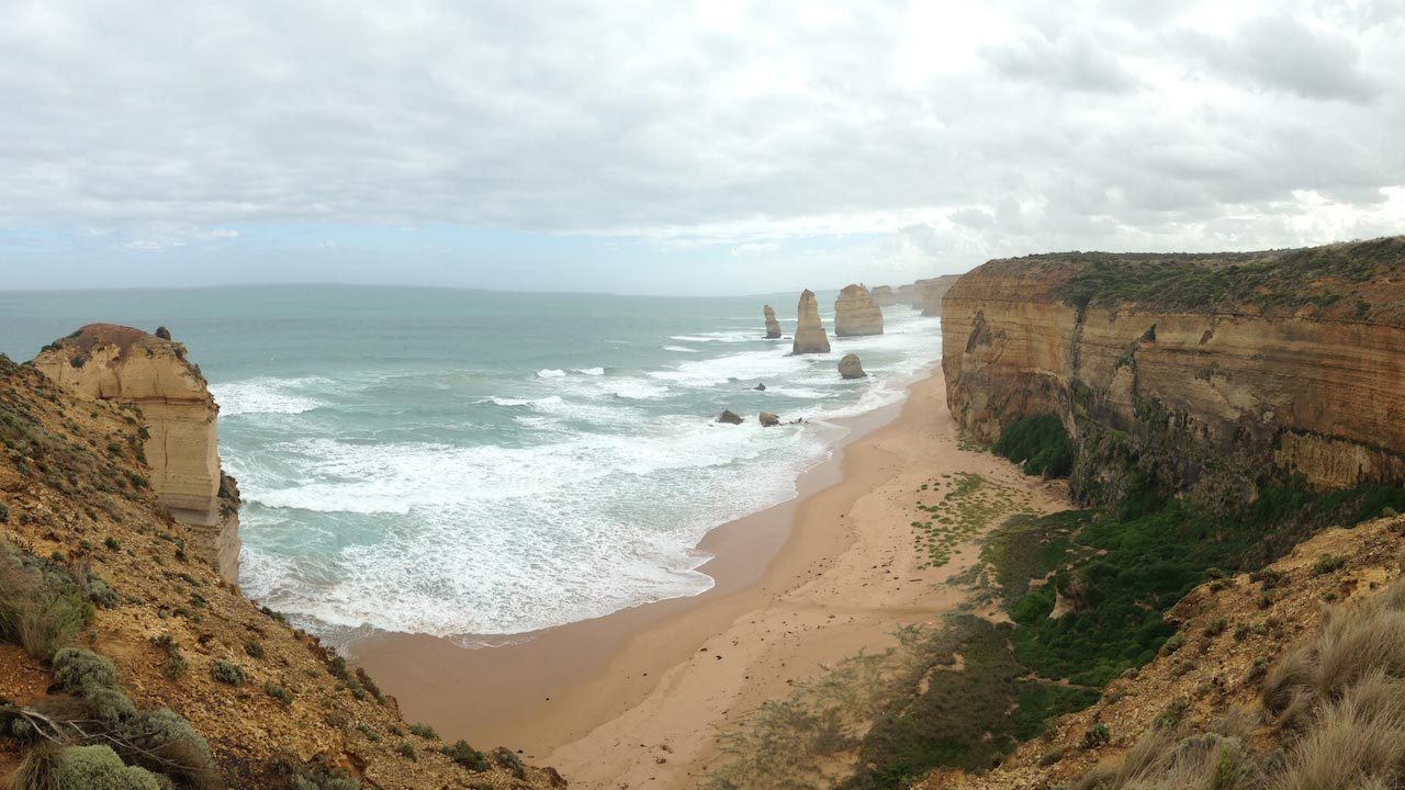 Limestone cliffs jutting out of the ocean as waves crash into the beach