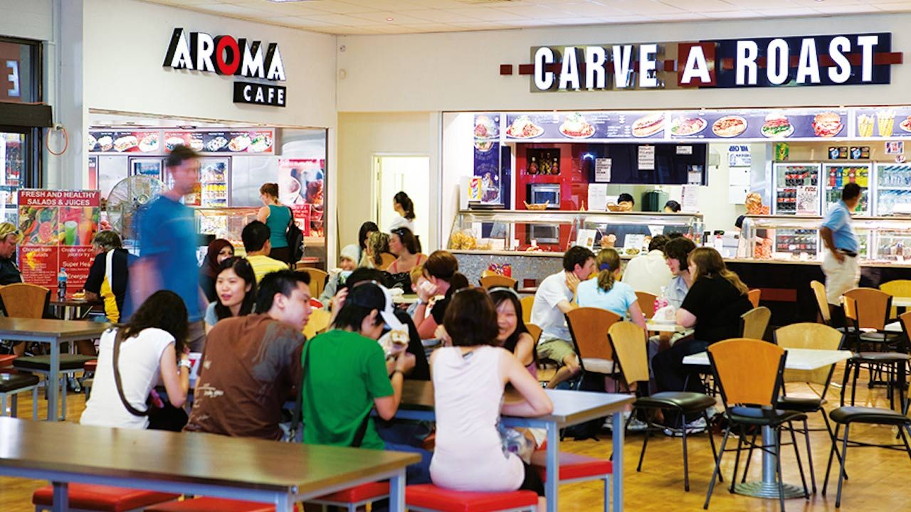 People sitting at tables in Murdoch University's student center in Perth, Australia