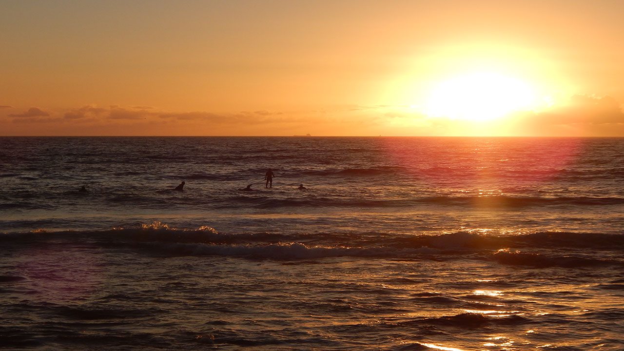 The sun sets behind the ocean's horizon in Newcastle, Australia