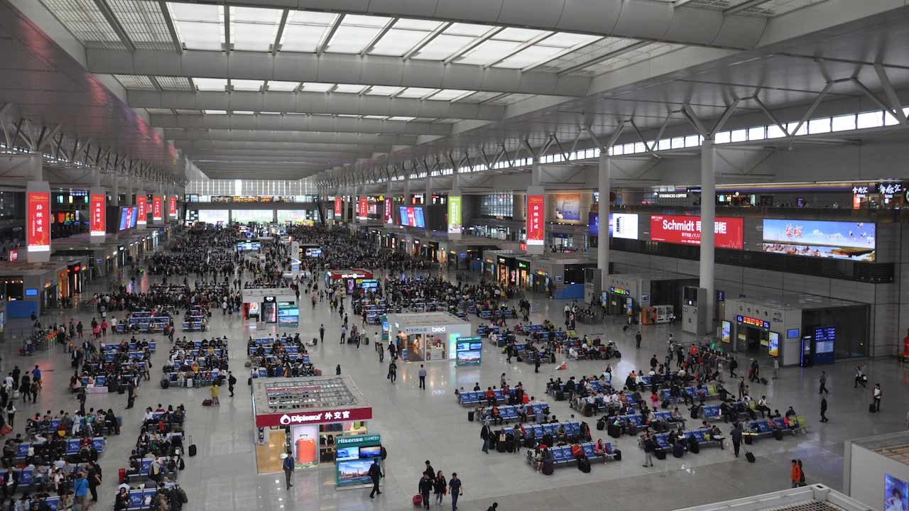 Inside Shanghai's busy bus station filled with advertisement screens and benches filled with people sitting