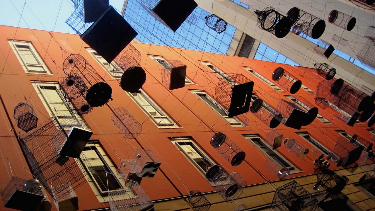 Bird cages hang in an alley surrounded by tall buildings in downtown Sydney