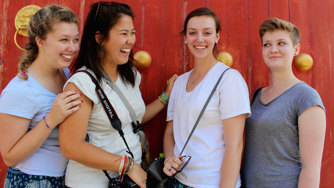 Four female students pose in front of a red and gold door in northern Thailand