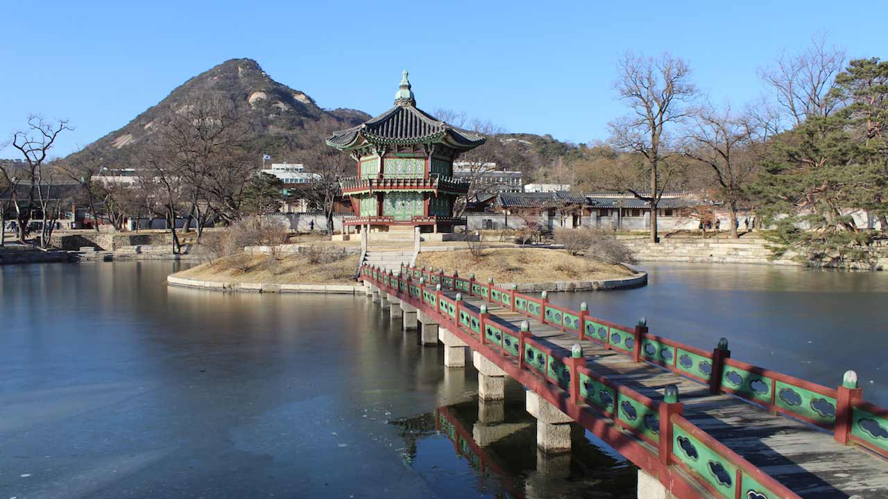 A red and green bridge leading to a Buddhist temple in Jeju, Korea