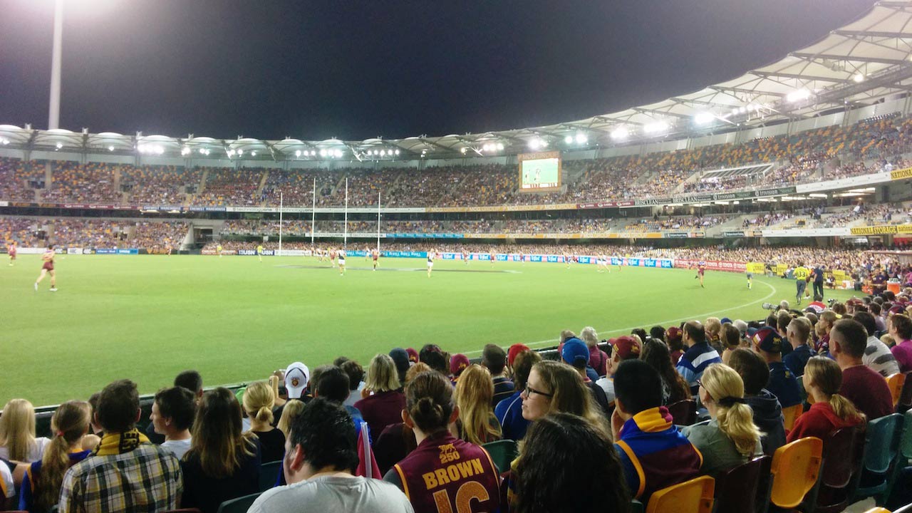 Fans sit in the stadium and watch the night time football match in Australia